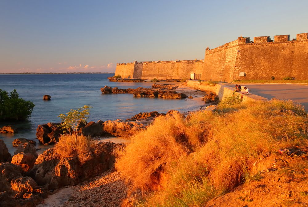 Historische Festungsmauer an der Küste Mosambiks bei Sonnenuntergang mit Blick auf das Meer und die koloniale Architektur der Ilha de Moçambique.