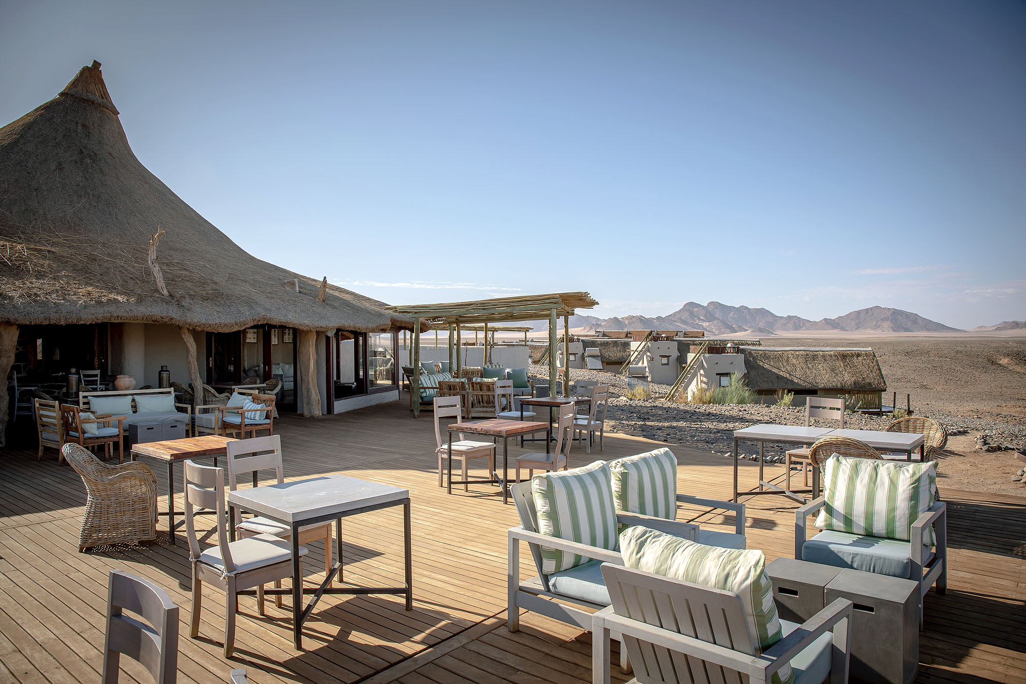 Großzügige Terrasse einer exklusiven Wüstenlodge mit Blick über die Weite der Namib-Wüste und die umliegenden Bergketten in Namibia.