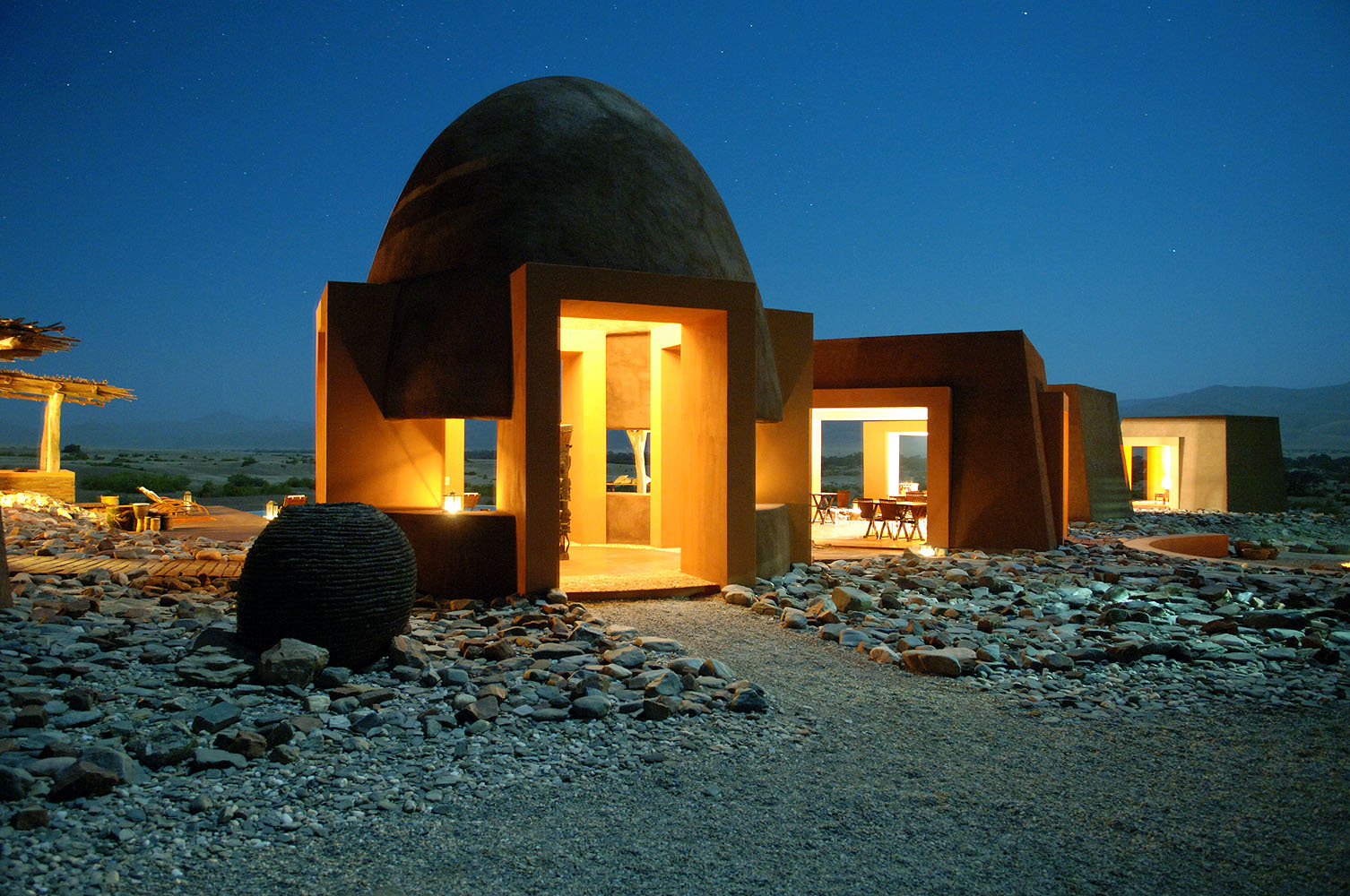 Exklusive Wüstenlodge in Namibia bei Nacht mit beleuchteter Architektur und klarem Sternenhimmel in der Namib-Wüste.