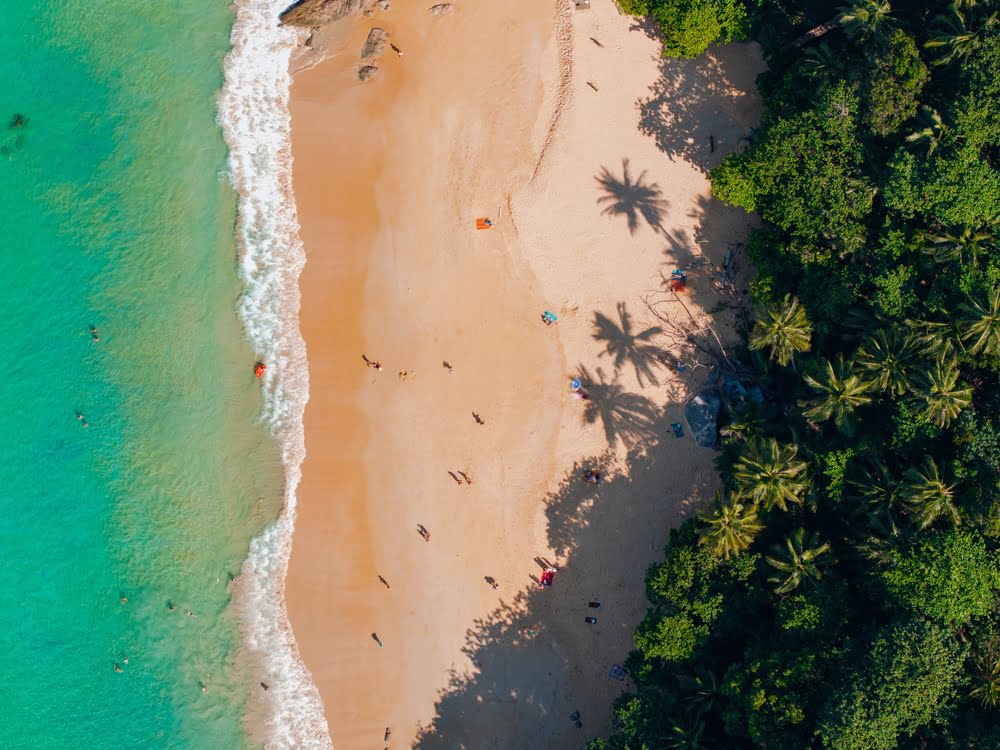 Luftaufnahme von Ilhéu das Rolas mit tropischem Sandstrand, türkisfarbenem Wasser, Palmen und dichter Vegetation im Golf von Guinea.