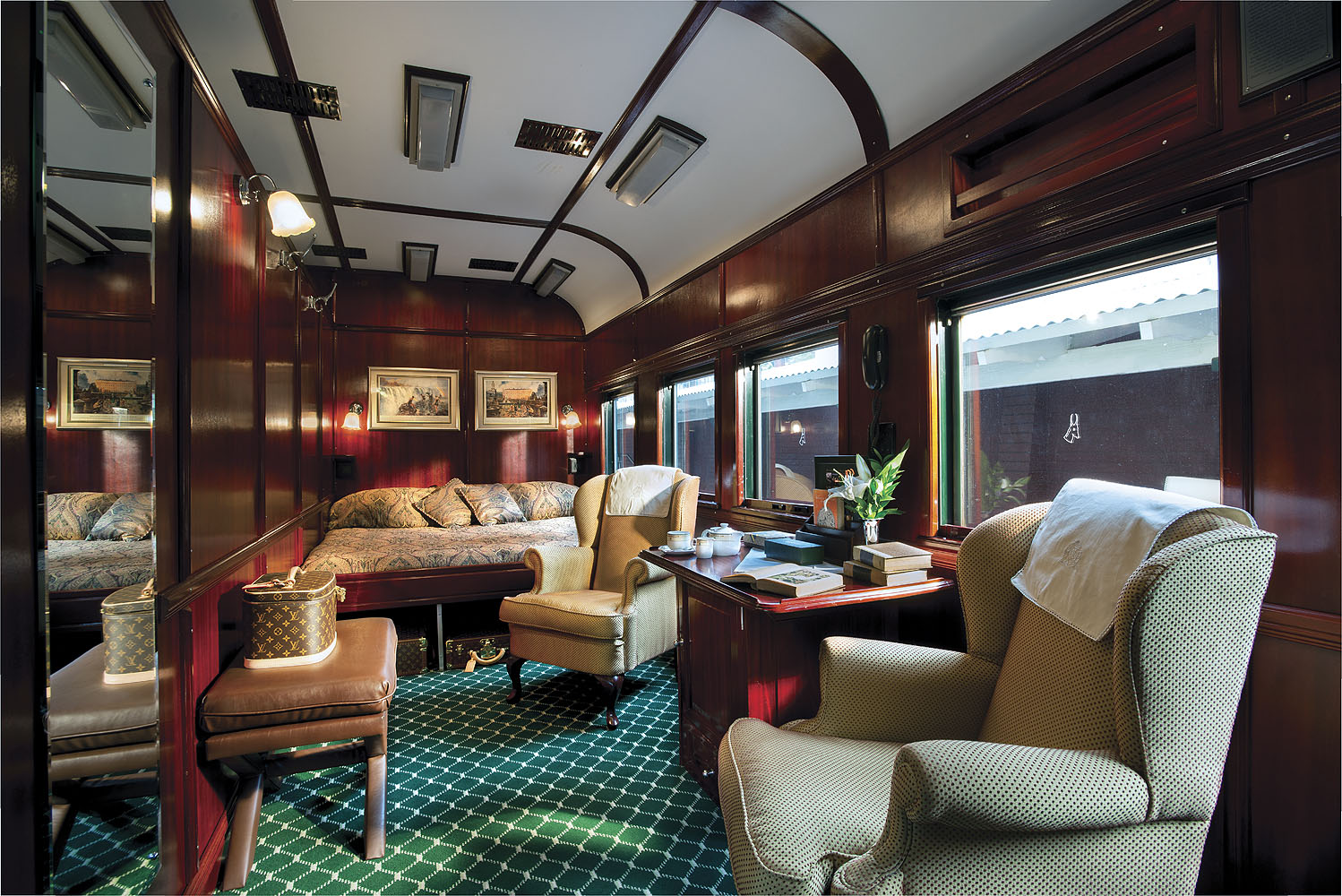 Großzügige Royal Suite im Luxuszug Rovos Rail mit edler Holzvertäfelung, komfortablen Sesseln und elegantem Wohnbereich.