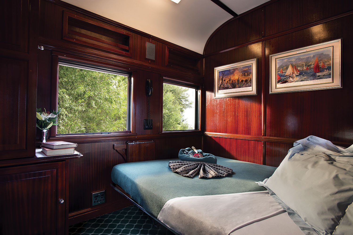 Elegantes Schlafabteil mit Doppelbett und edlen Holzvertäfelungen an Bord des Luxuszuges Rovos Rail.