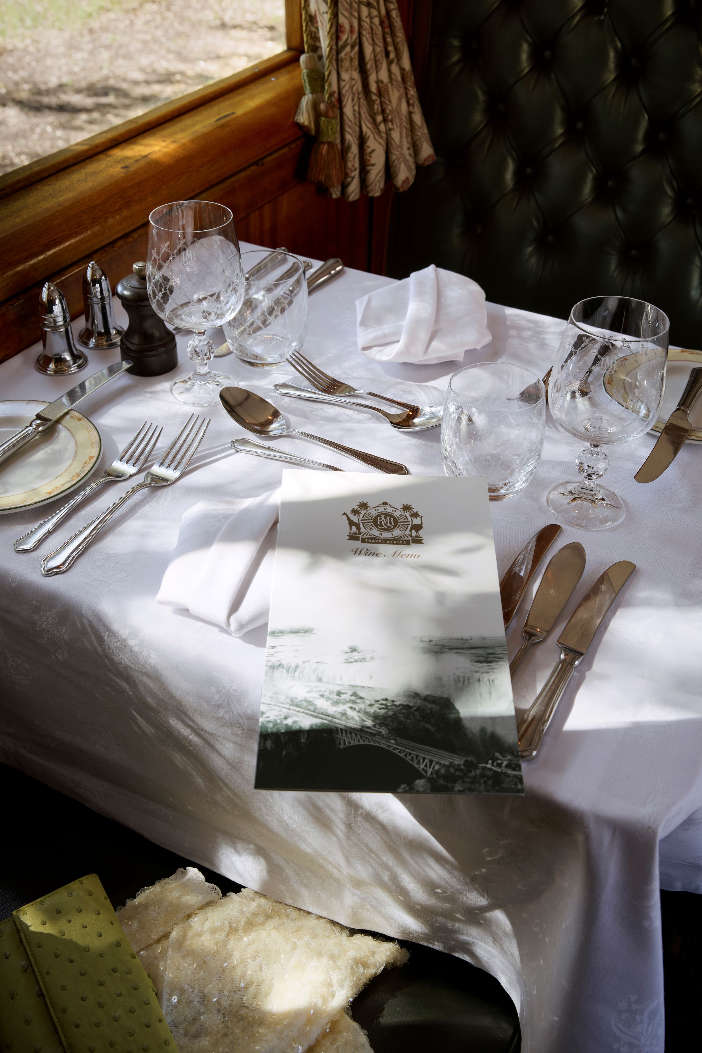 Elegant gedeckter Tisch mit Weinmenü im Speisewagen des Rovos Rail Luxuszuges.