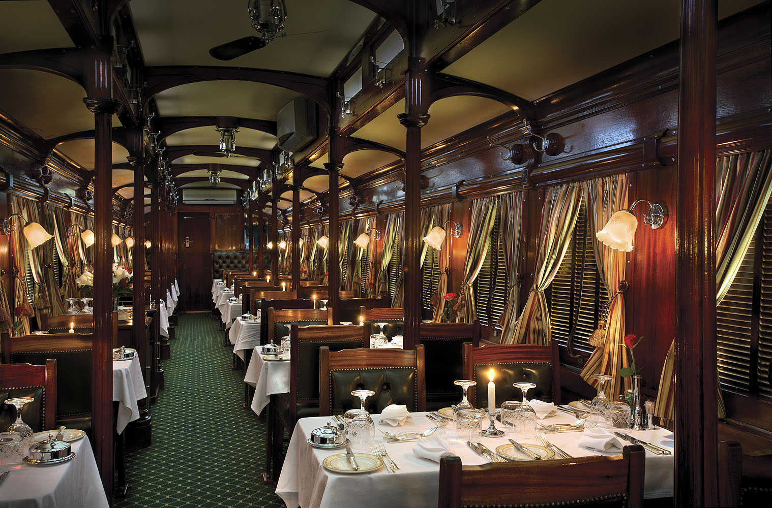 Stilvoll eingerichteter Speisewagen des Luxuszuges Rovos Rail mit gedeckten Tischen und nostalgischem Ambiente.